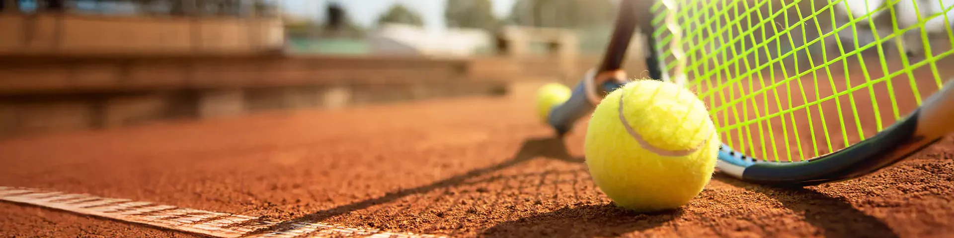 Nahaufnahme eines Tennisball mit Tennisschläger auf einem Sandplatz